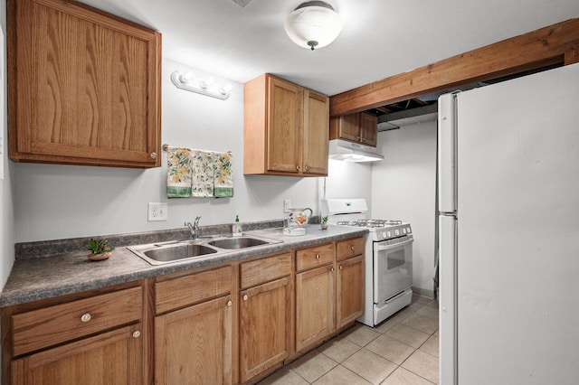 kitchen featuring white appliances, a sink, under cabinet range hood, light tile patterned floors, and dark countertops