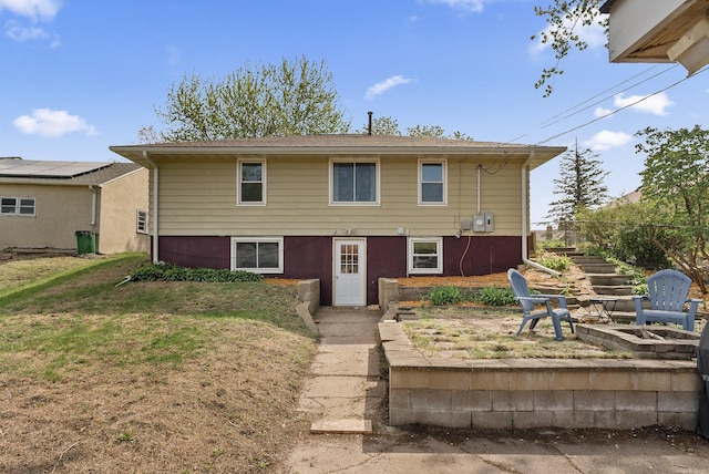 rear view of property featuring an outdoor fire pit, stairs, and a lawn