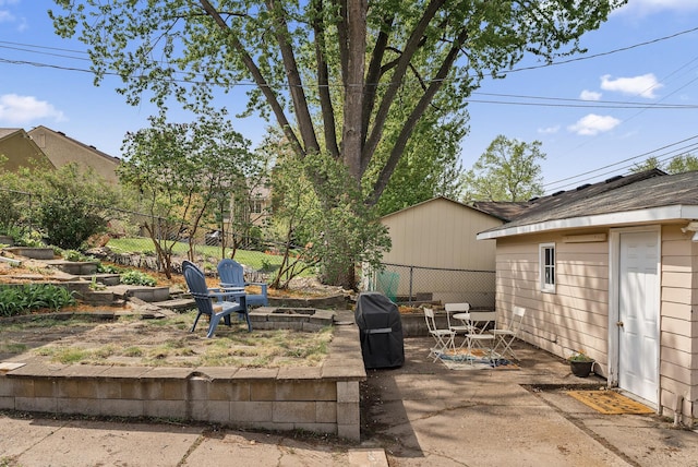 view of patio / terrace featuring fence, grilling area, an outdoor fire pit, and an outdoor structure