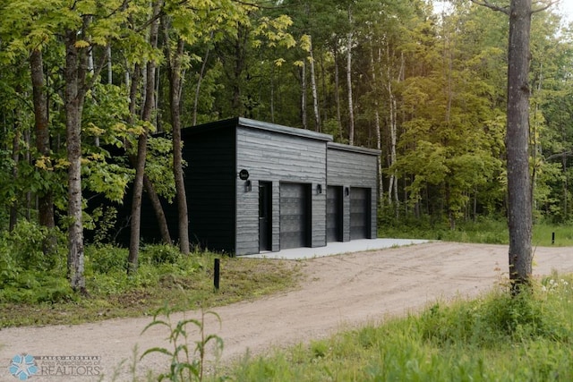 21574 State 200, Rice Twp, MN 56621 - garage with dirt driveway and a view of trees