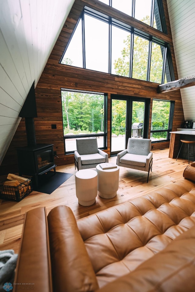 21574 State 200, Rice Twp, MN 56621 - living room featuring wooden walls, a wood stove, and high vaulted ceiling