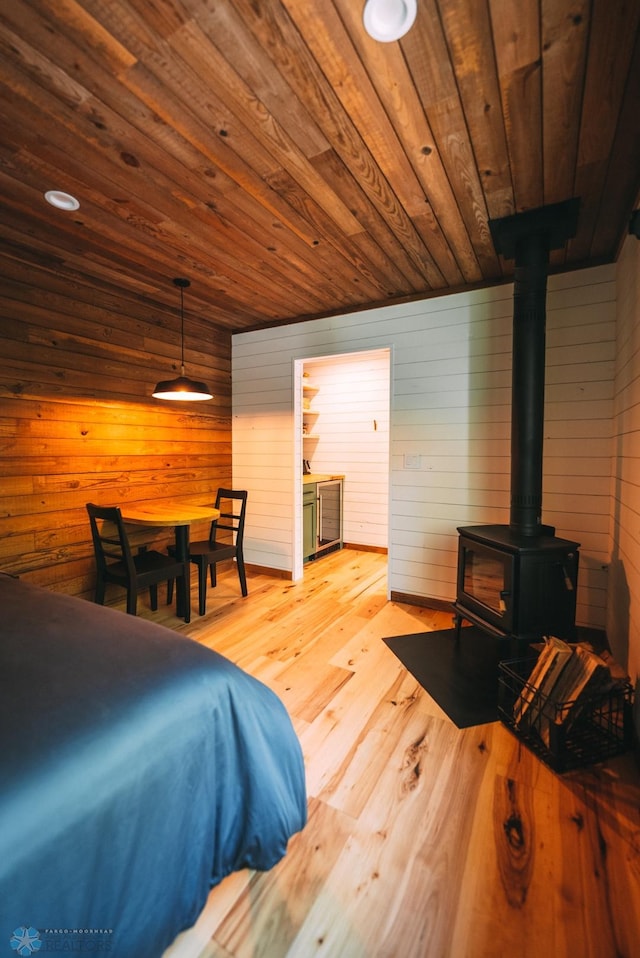 21574 State 200, Rice Twp, MN 56621 - bedroom with a wood stove, light wood-style floors, wooden ceiling, and wood walls