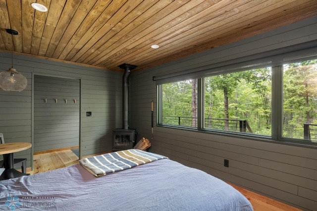 21574 State 200, Rice Twp, MN 56621 - bedroom featuring wooden ceiling, wood finished floors, a wood stove, and wood walls