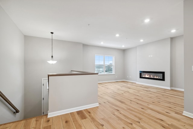6746 Wildflower Way, Minnetrista, MN 55331 - unfurnished living room with light wood-type flooring, recessed lighting, baseboards, and a glass covered fireplace