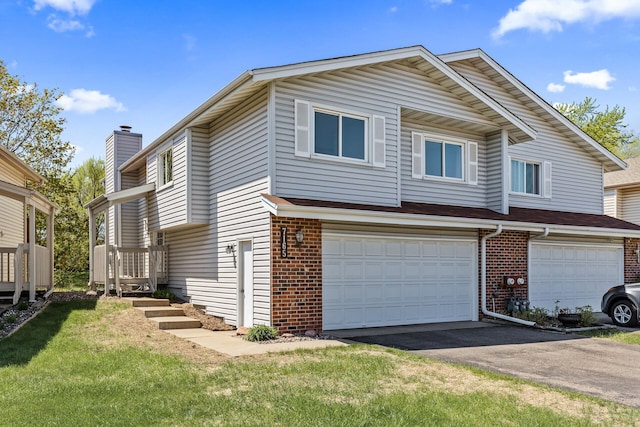 view of property with brick siding, an attached garage, driveway, a chimney, and a front lawn