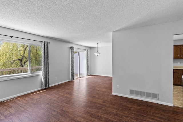 empty room featuring wood finished floors, a textured ceiling, and baseboards