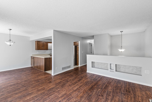 empty room with a textured ceiling, dark wood-style flooring, and baseboards