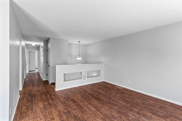 spare room featuring dark wood-type flooring, baseboards, and a textured ceiling