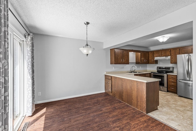 kitchen with stainless steel appliances, range hood, a sink, a peninsula, and light countertops