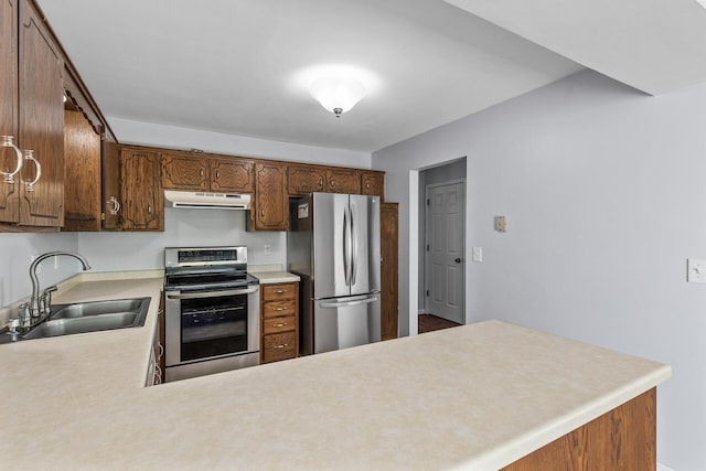 kitchen with stainless steel appliances, a sink, under cabinet range hood, light countertops, and a peninsula