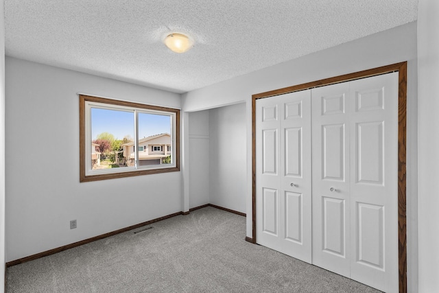 unfurnished bedroom featuring carpet, a textured ceiling, a closet, and baseboards