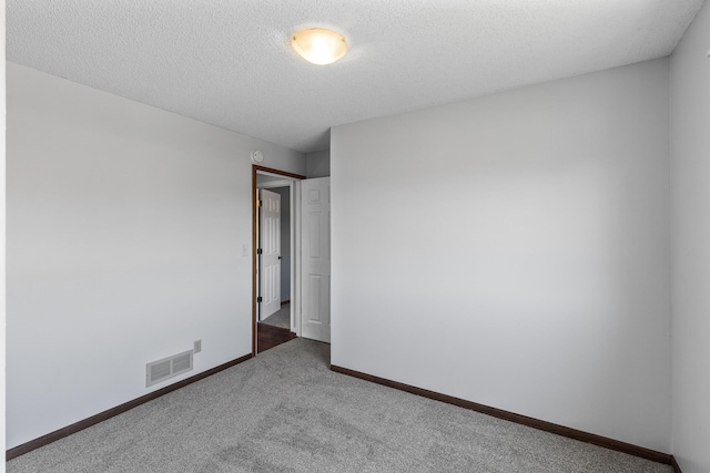 carpeted empty room featuring baseboards and a textured ceiling