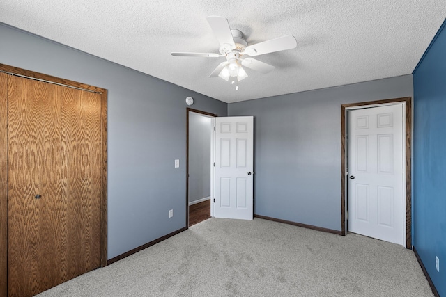 unfurnished bedroom with carpet, a textured ceiling, baseboards, and a ceiling fan