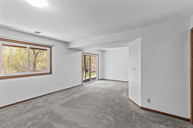 spare room with carpet, a textured ceiling, and baseboards