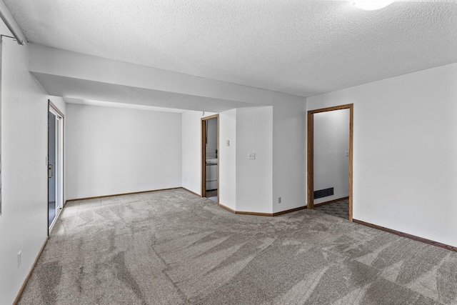 carpeted spare room with a textured ceiling and baseboards