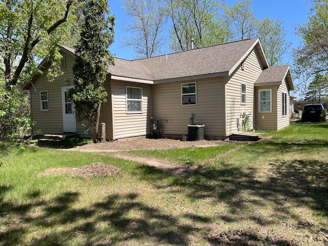 back of property with roof with shingles, a yard, and central air condition unit