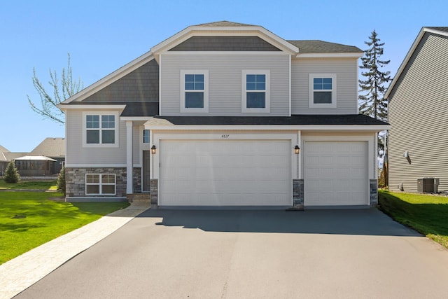craftsman inspired home featuring stone siding, a garage, a front lawn, central air condition unit, and driveway