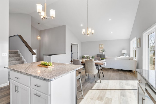 kitchen featuring light stone countertops, an inviting chandelier, open floor plan, white cabinets, and light wood-type flooring