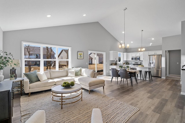 living area with recessed lighting, a chandelier, wood finished floors, and high vaulted ceiling