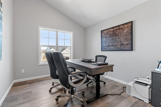 office space with lofted ceiling, baseboards, and light wood-type flooring