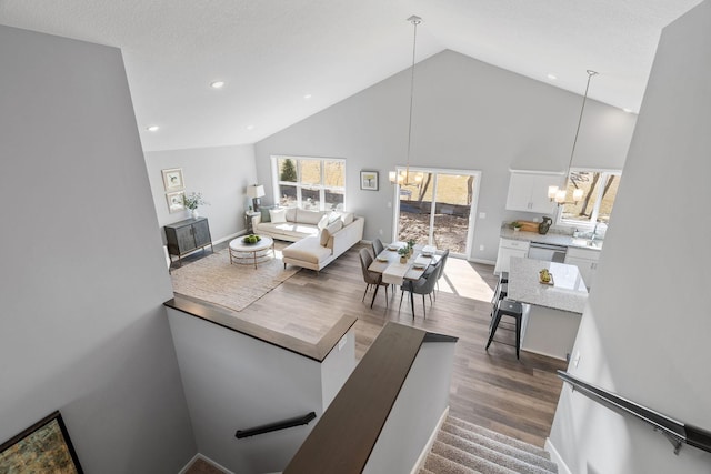 living area with high vaulted ceiling, a notable chandelier, baseboards, dark wood-style floors, and recessed lighting
