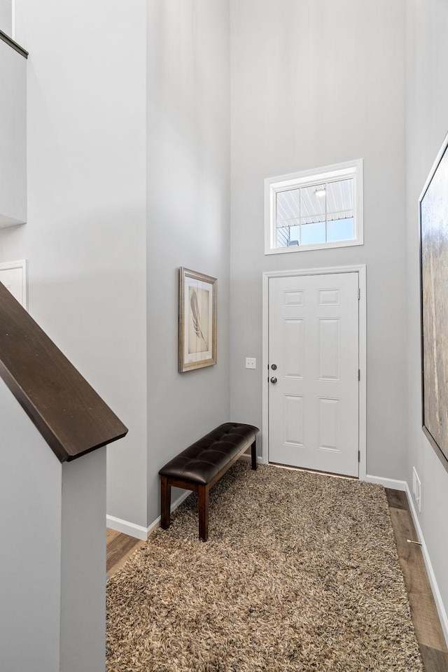 foyer featuring visible vents, wood finished floors, baseboards, and a high ceiling