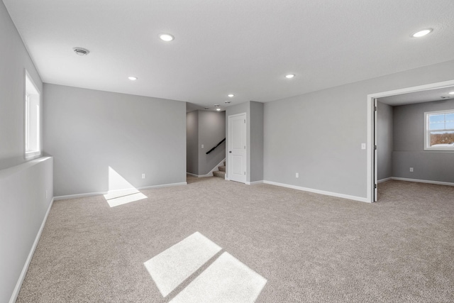 interior space with baseboards, light carpet, and recessed lighting