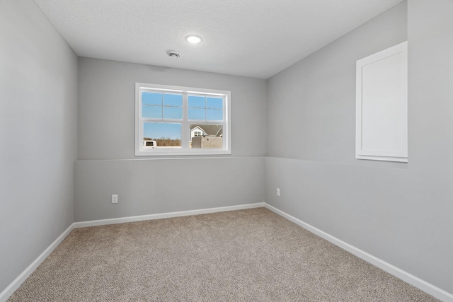 empty room featuring a textured ceiling, carpet flooring, and baseboards