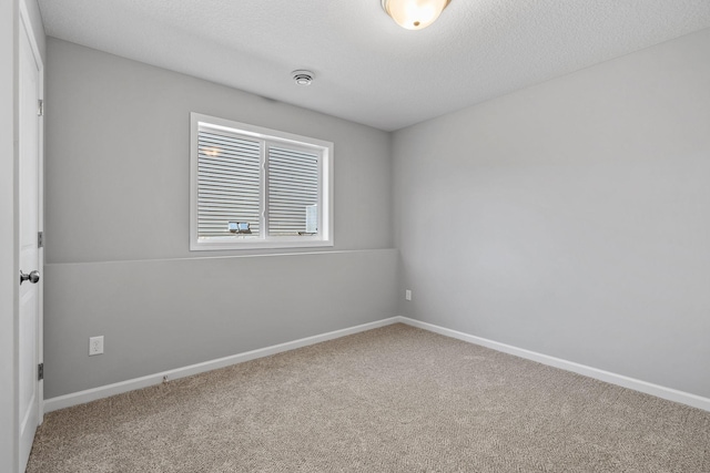 empty room featuring carpet, a textured ceiling, and baseboards