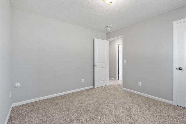 spare room featuring a textured ceiling, baseboards, and carpet floors