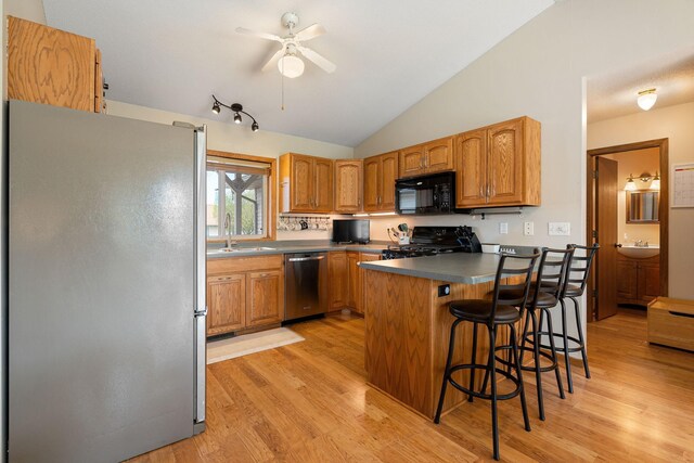 404 6th St NW, New Richland, MN 56072 - kitchen featuring appliances with stainless steel finishes, a sink, ceiling fan, light wood finished floors, and a peninsula