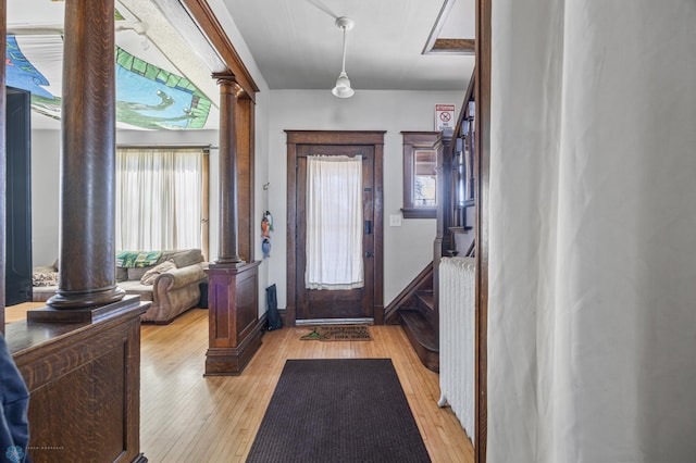 entrance foyer featuring baseboards, light wood-type flooring, and decorative columns