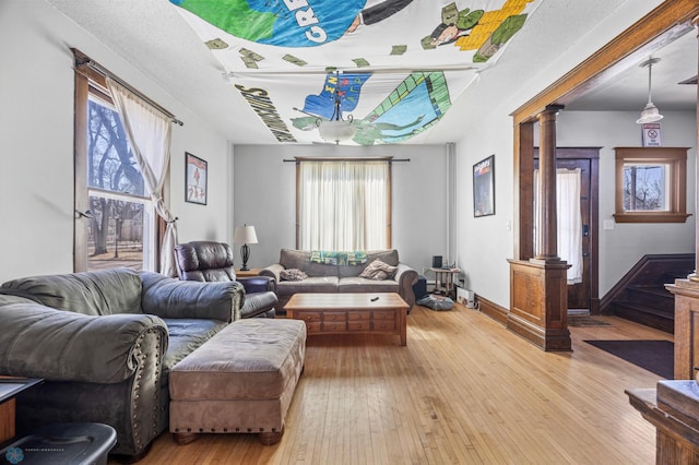living room with baseboards, light wood-type flooring, and decorative columns