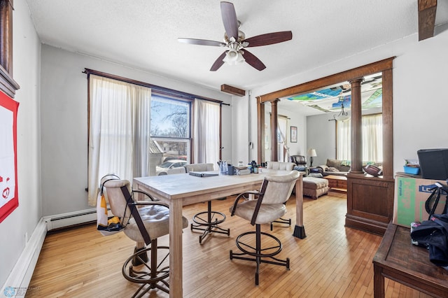 dining space with light wood-style floors, a healthy amount of sunlight, ceiling fan, and decorative columns
