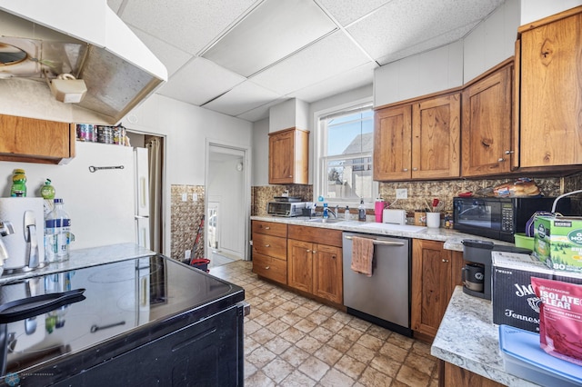 kitchen featuring light countertops, brown cabinetry, black appliances, and a paneled ceiling