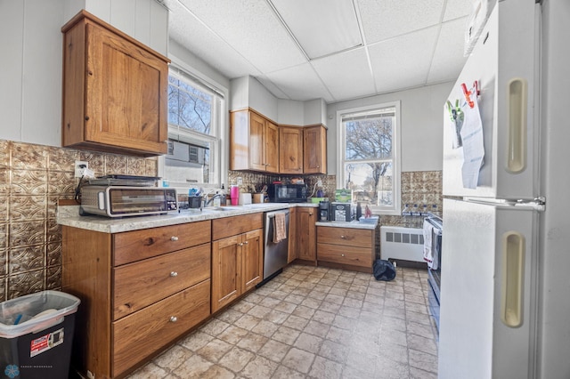 kitchen with brown cabinets, freestanding refrigerator, stainless steel dishwasher, light countertops, and black microwave