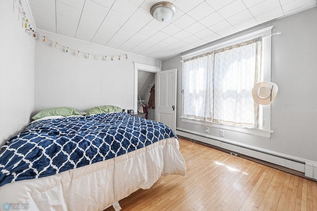 bedroom featuring a baseboard heating unit and wood-type flooring