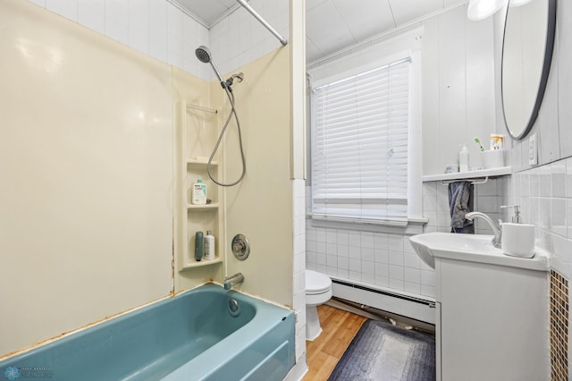 full bathroom with tile walls, a baseboard heating unit, toilet,  shower combination, and wood finished floors