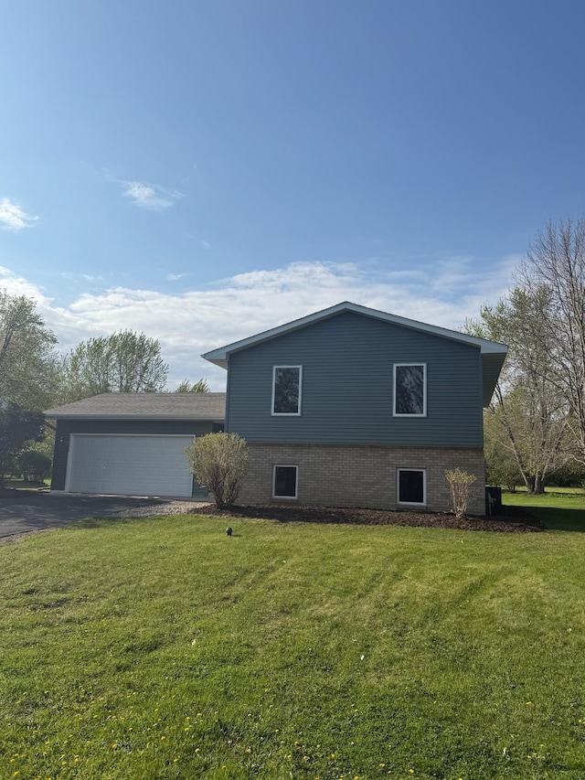 view of side of property featuring driveway, a lawn, and an attached garage