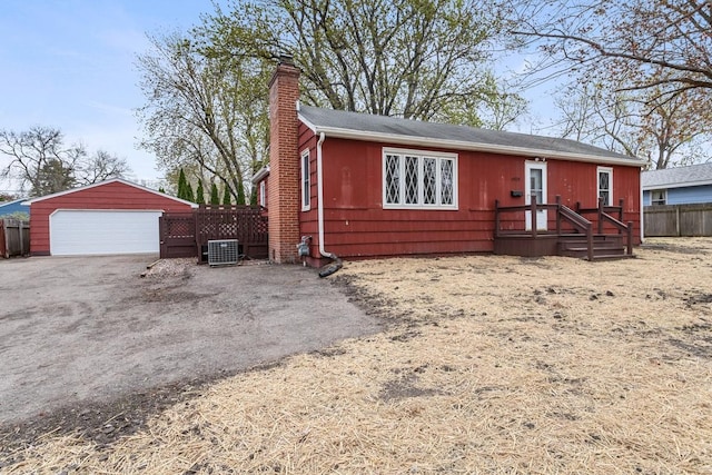 view of front facade featuring a chimney, a detached garage, fence, central AC, and an outbuilding