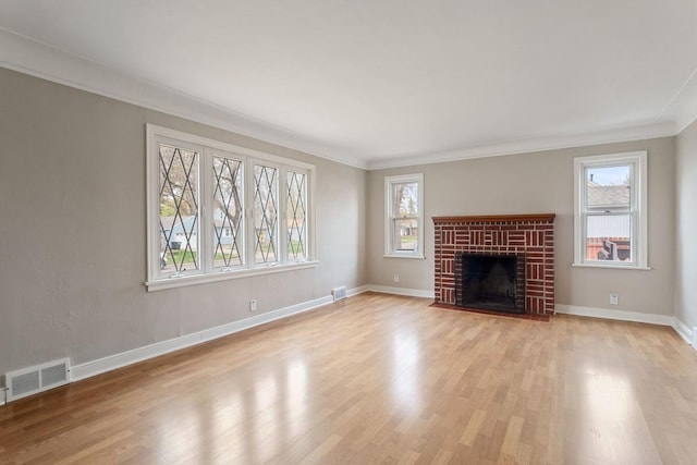 unfurnished living room featuring ornamental molding, light wood-type flooring, baseboards, and a brick fireplace