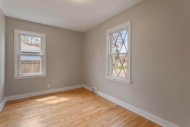 unfurnished room with plenty of natural light, baseboards, and light wood-style floors