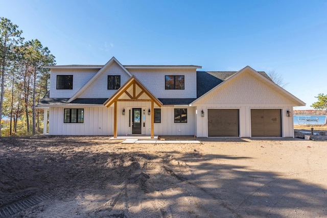 modern farmhouse featuring an attached garage, driveway, board and batten siding, and a porch