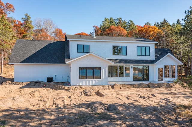 rear view of house featuring roof with shingles, central AC unit, and a patio