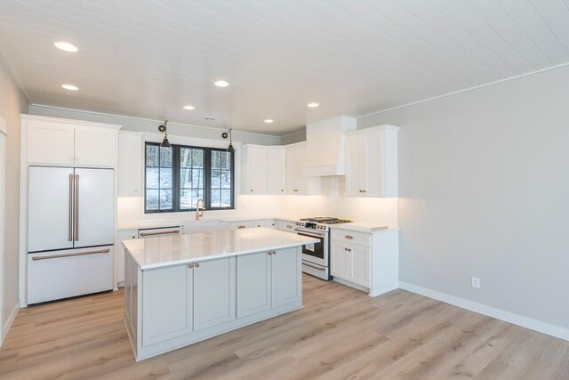 kitchen featuring premium appliances, a sink, a center island, premium range hood, and white cabinetry