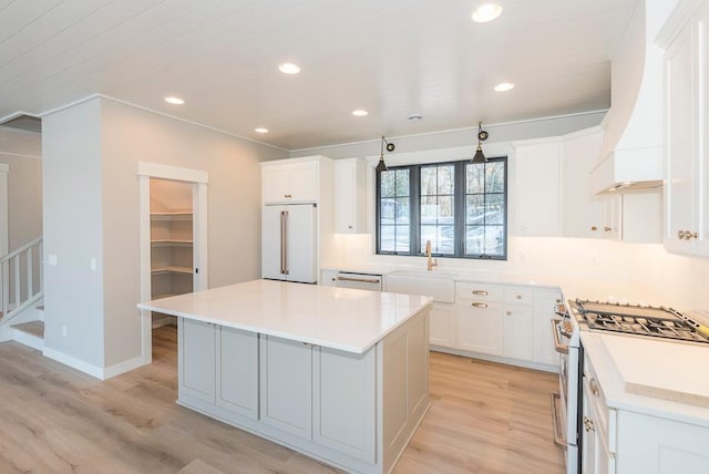 kitchen featuring stainless steel gas stove, built in refrigerator, light wood-style floors, a sink, and recessed lighting