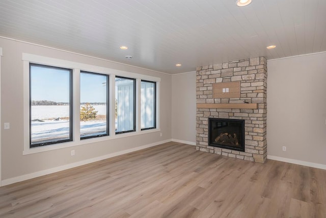 unfurnished living room with light wood-style flooring, recessed lighting, baseboards, a stone fireplace, and wooden ceiling
