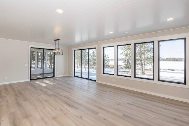 empty room featuring a chandelier, baseboards, light wood-style flooring, and recessed lighting