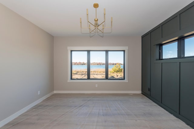 spare room with a chandelier, baseboards, and a water view