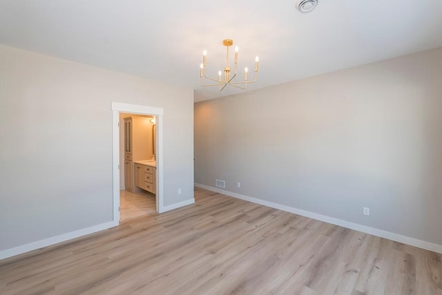unfurnished room featuring a chandelier, light wood finished floors, and baseboards